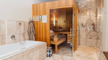 Un baño moderno con sauna de madera, ducha con mampara de vidrio y bañera.