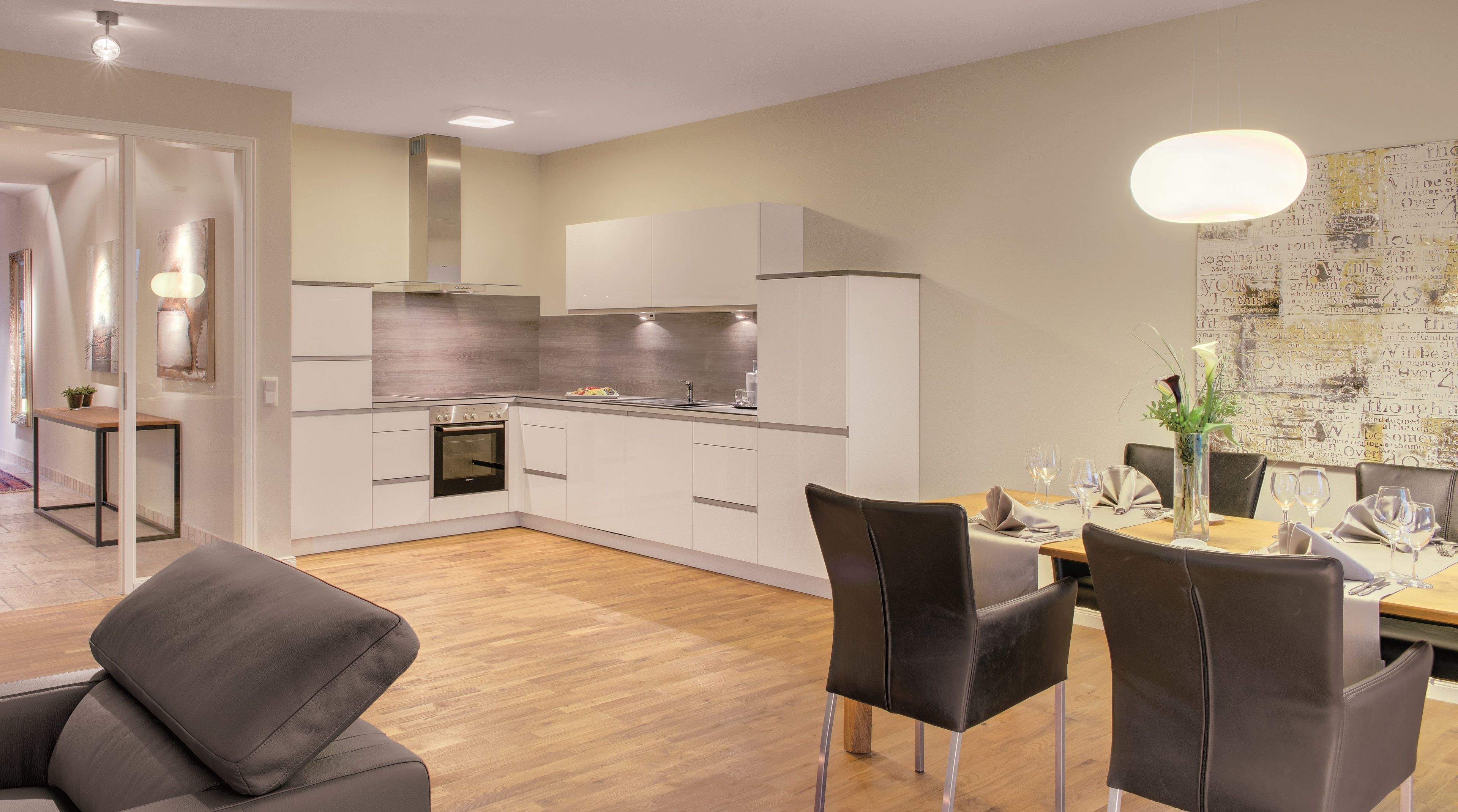 Eine moderne Küche mit weißen Schränken, einem eingebauten Backofen und einer Edelstahl-Dunstabzugshaube.