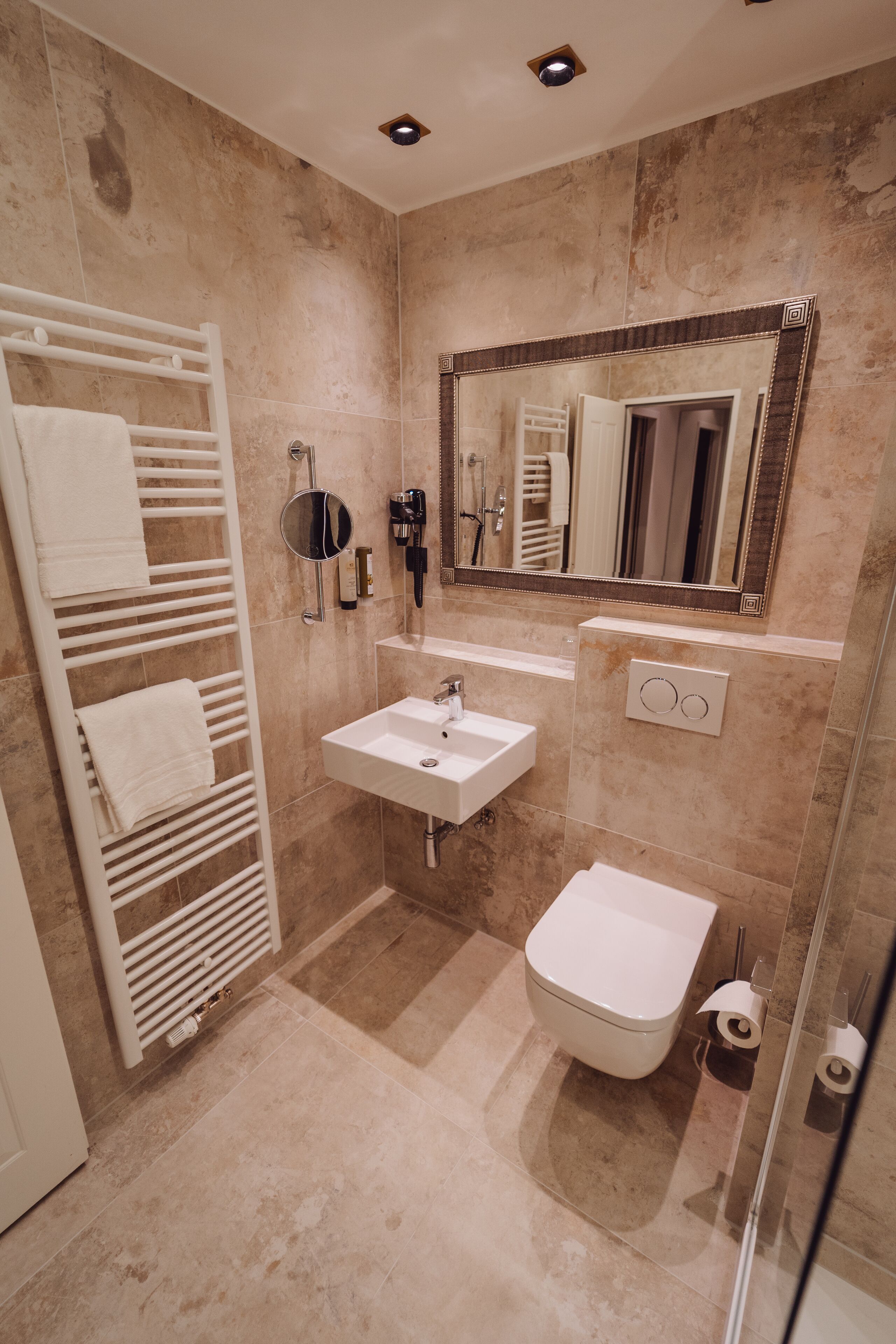 Un baño con lavamanos, espejo y retrete blancos.