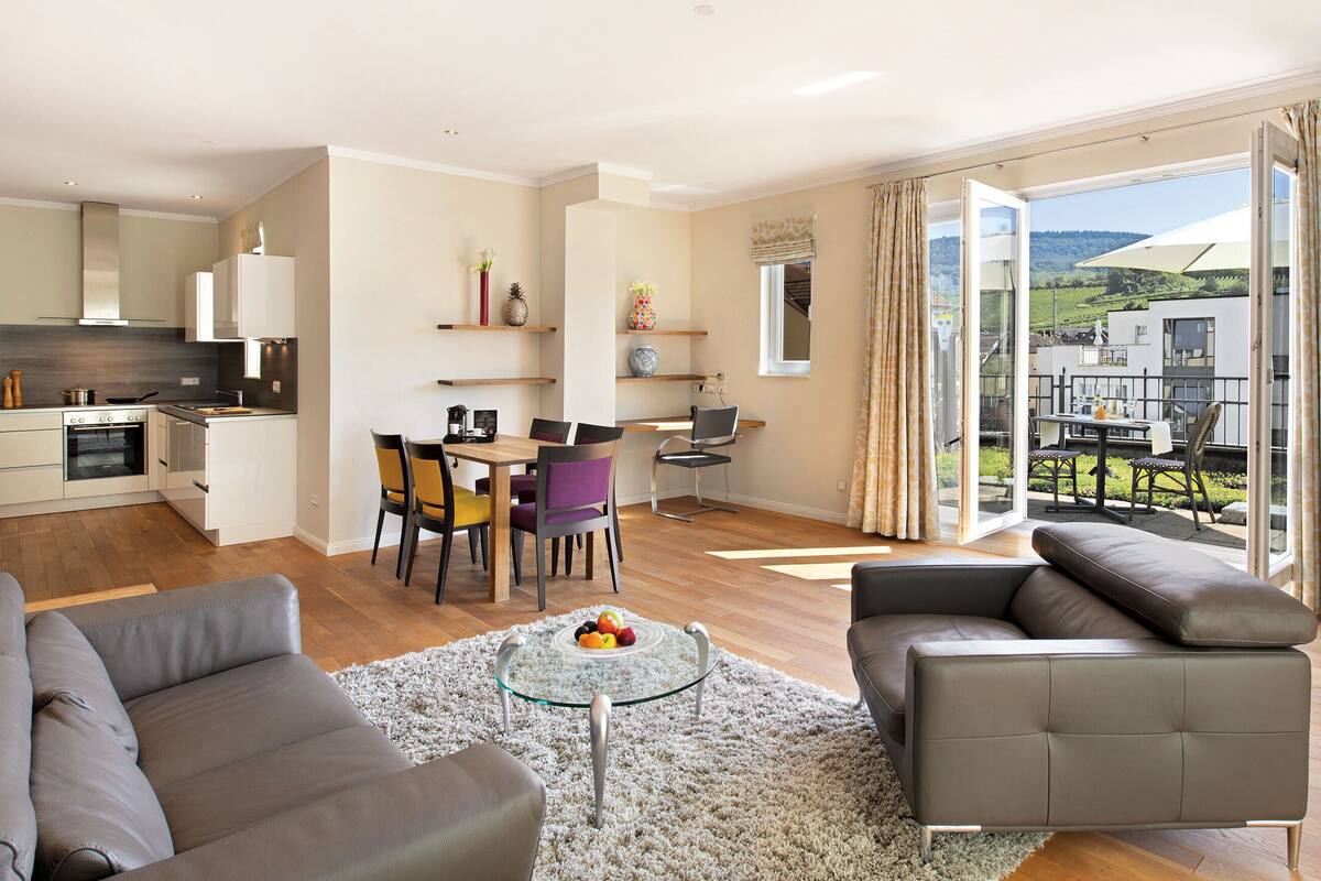 Un appartement moderne comprenant un coin repas, une cuisine, un salon et un balcon avec vue.