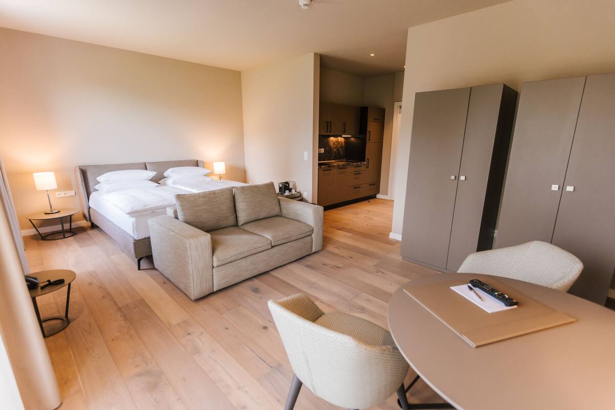 Une chambre d’hôtel moderne équipée d’un lit, d’un canapé, d’une table à manger et d’une kitchenette.
