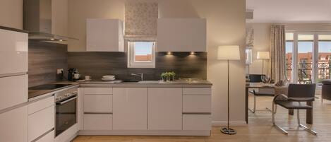 A modern kitchen with a central island, built-in oven, and a dining area with a table and chairs.