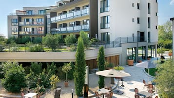 Un hôtel moderne doté d’une terrasse extérieure, d’un patio couvert et d’un bâtiment à plusieurs étages avec des balcons.