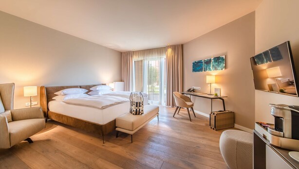 Ein Hotelzimmer mit einem großen Bett, einem Schreibtisch, einem Sessel, einer Couch und einem kleinen Tisch.