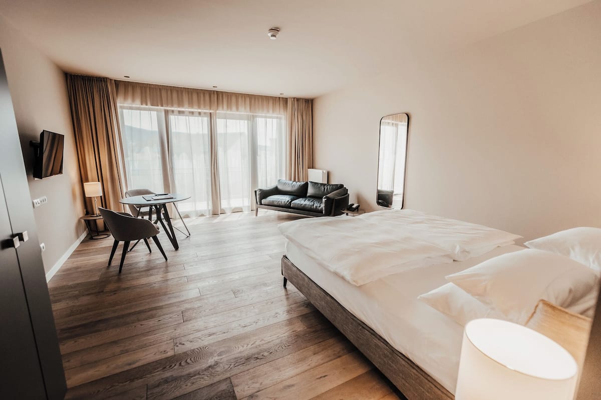 Une chambre d’hôtel avec un grand lit, un bureau avec une chaise, un canapé et un téléviseur fixé au mur.