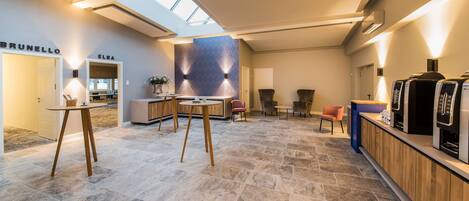 Een ruime lobby met een hoge plafond, een receptiebalie en een zithoek met stoelen.