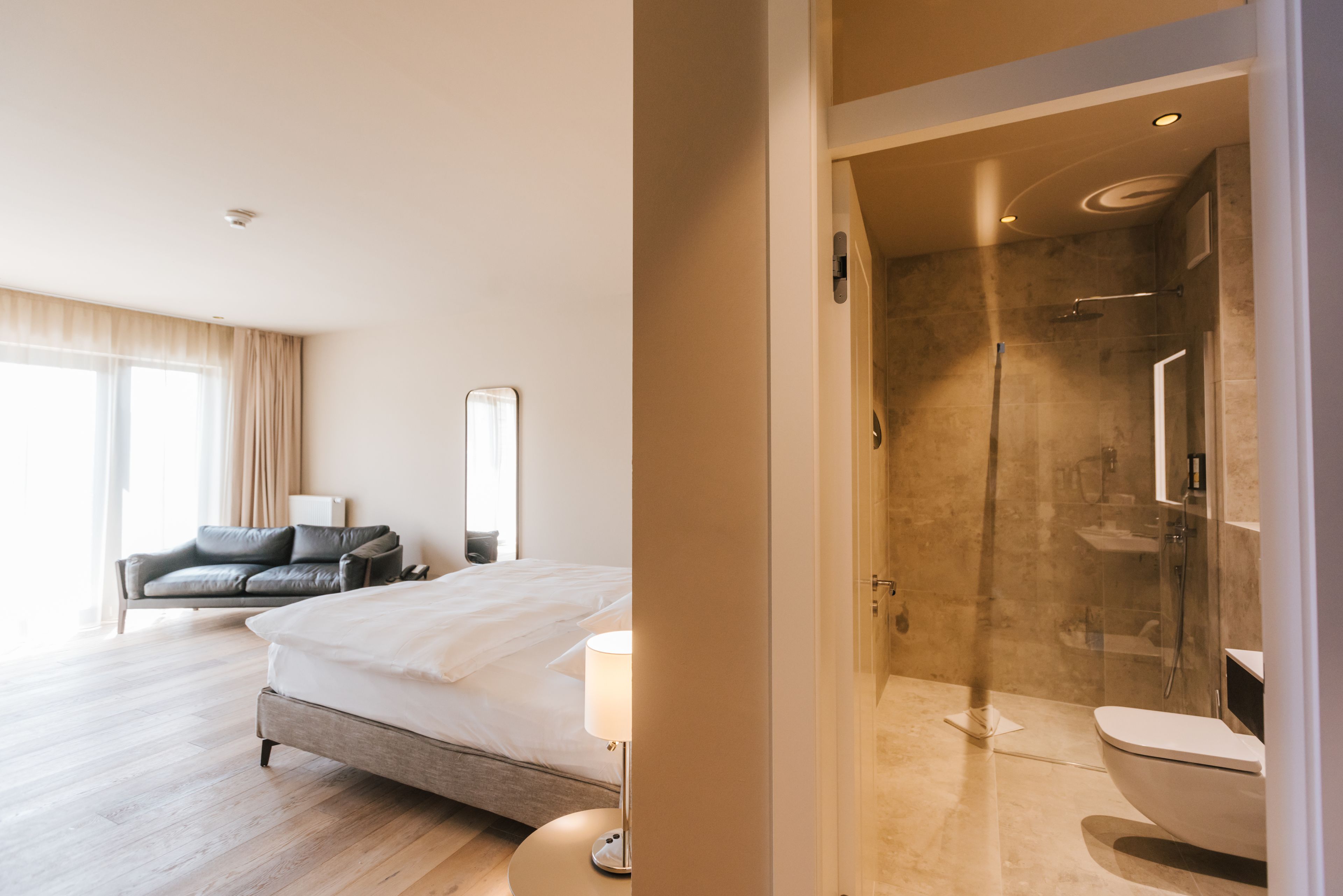 Ett hotellrum med en stor säng, en soffa och ett badrum med dusch och toalett.