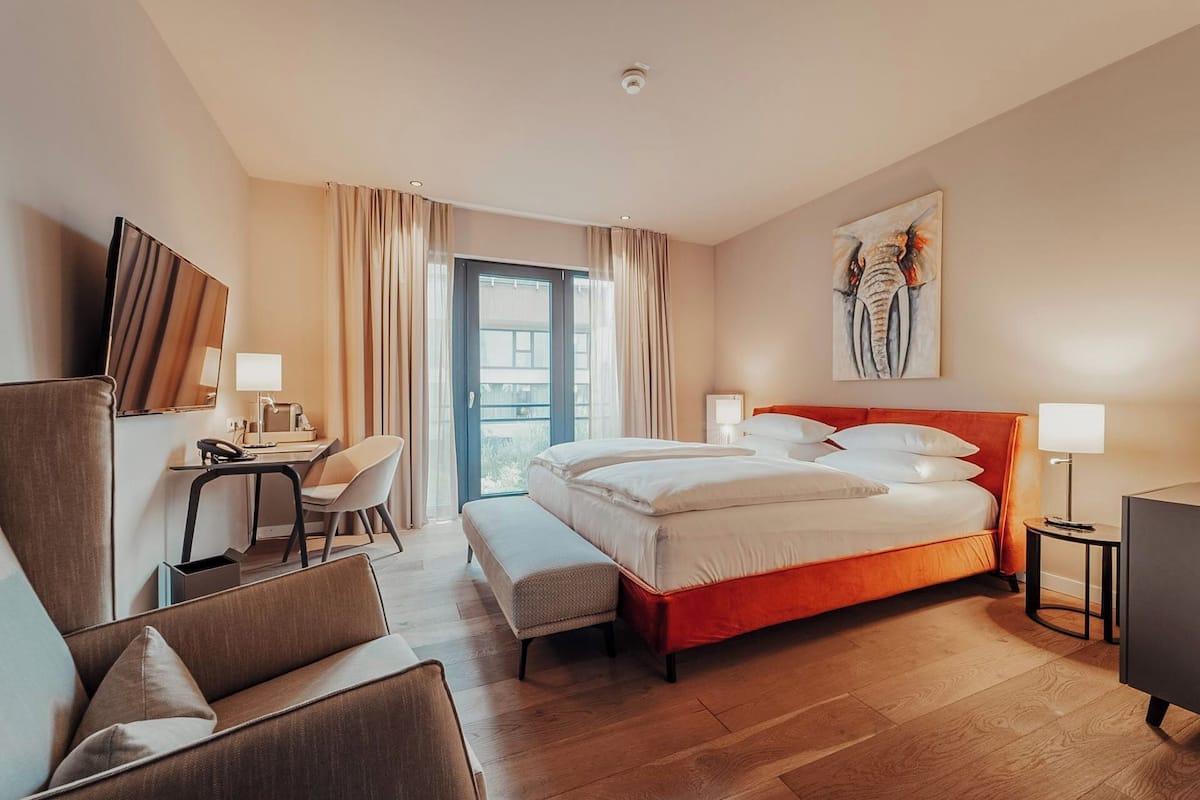 Une chambre d’hôtel avec un lit, un bureau, une chaise et une œuvre d’art au mur.