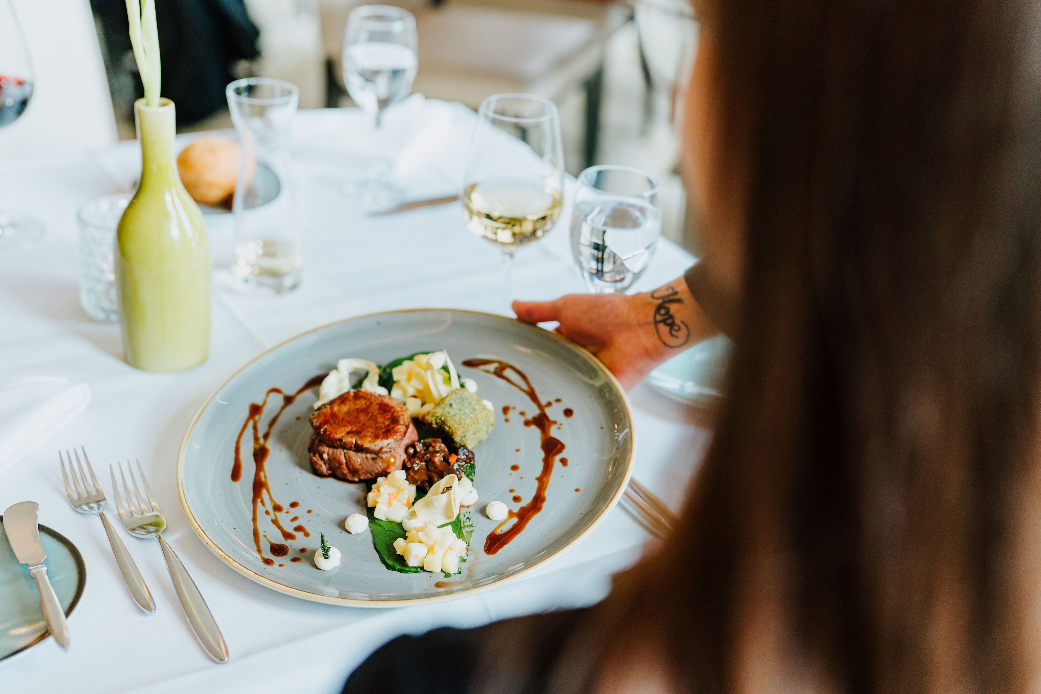 A dining table with a plate of food, a bottle, and glasses.