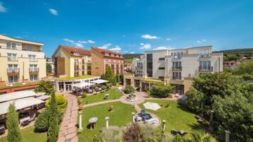 A courtyard with a central fountain, surrounded by buildings with balconies and outdoor seating areas.