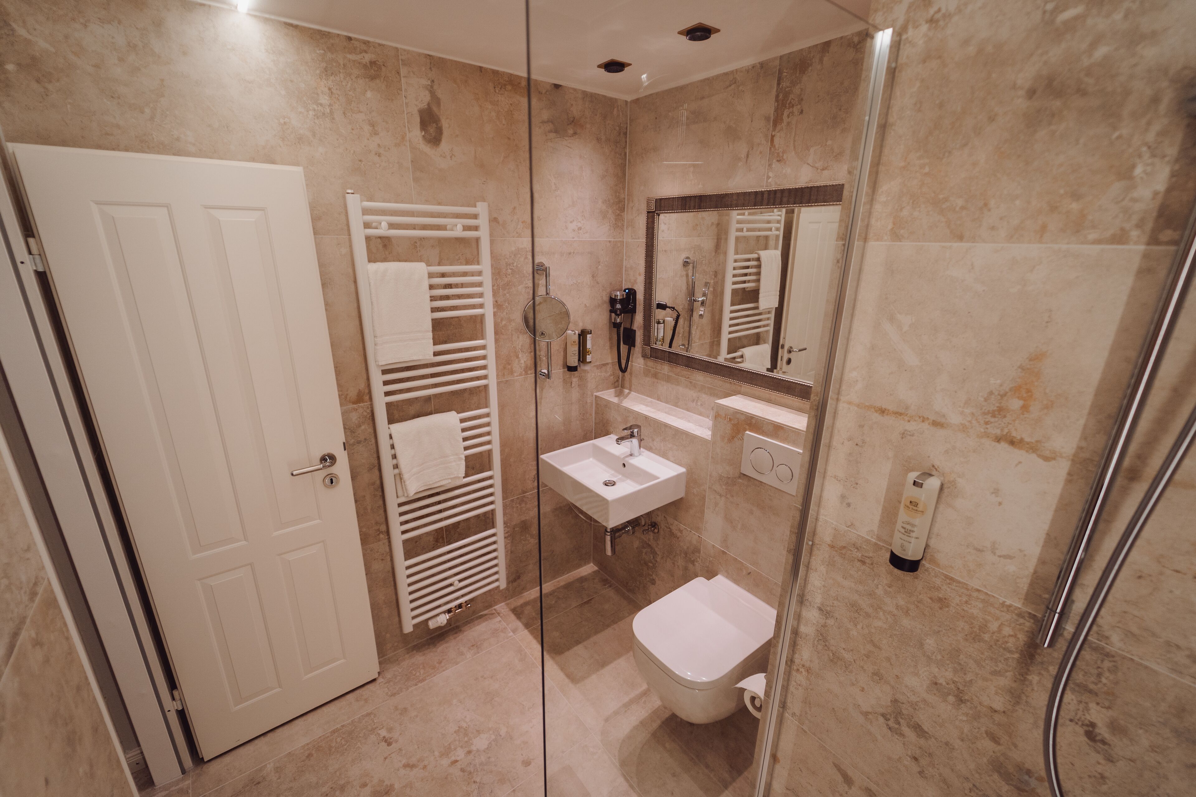 Un baño moderno con ducha de vidrio, lavamanos blanco y un inodoro.