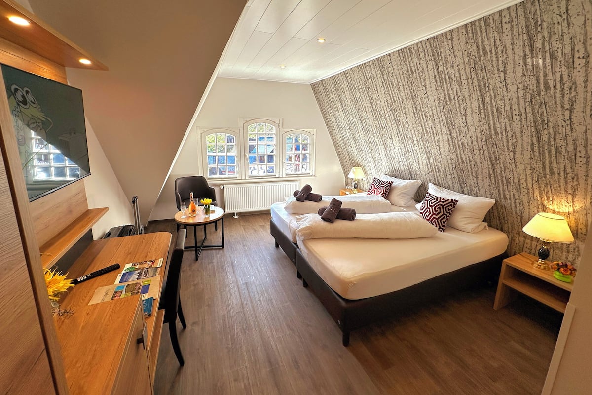 Ein Schlafzimmer mit einem großen Bett, einem Schreibtisch mit Stuhl, einem Fenster mit Aussicht und einer Heizung.