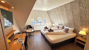 A bedroom with a large bed, a desk with a chair, a window with a view, and a radiator.