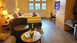 A hotel room with a bed, a desk, a chair, a sofa, a table with a vase of flowers, and a television. - HOTEL AM MARKT (Bacharach)