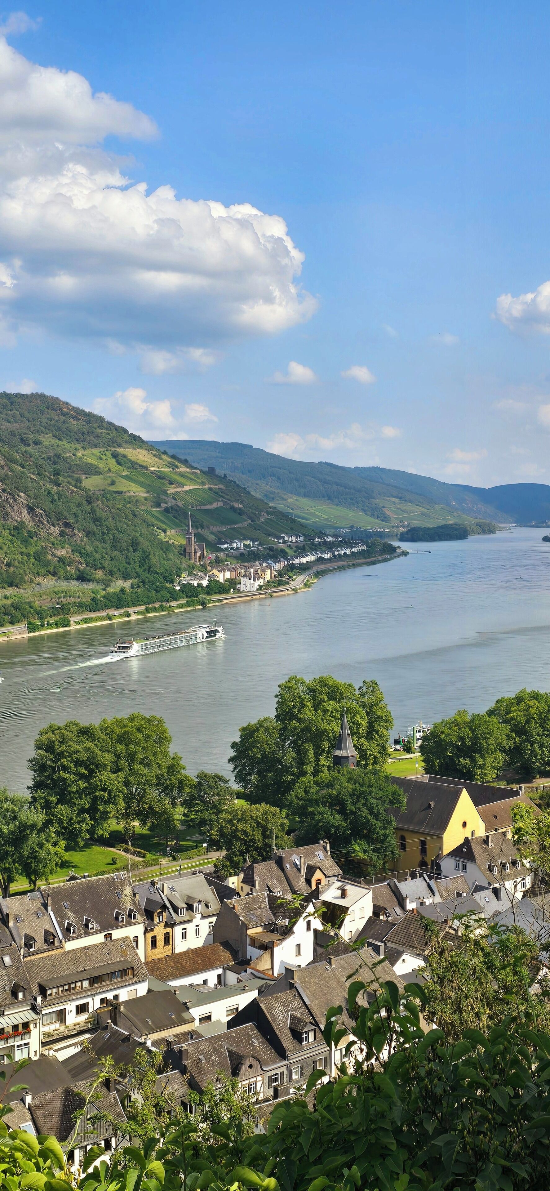 Une rivière où l’on peut naviguer, bordée de collines verdoyantes et traversée par une ville aux maisons traditionnelles.