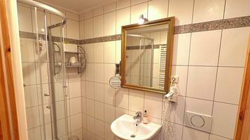 Un baño con cabina de ducha de vidrio, lavamanos con espejo e inodoro.
