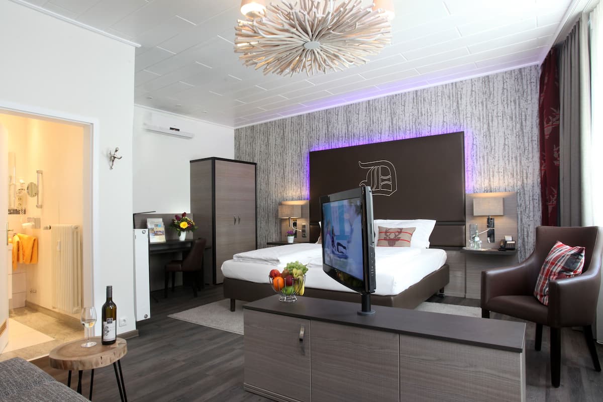 Ein modernes Hotelzimmer mit einem großen Bett, einem Schreibtisch, einem Fernseher und einer Essecke.