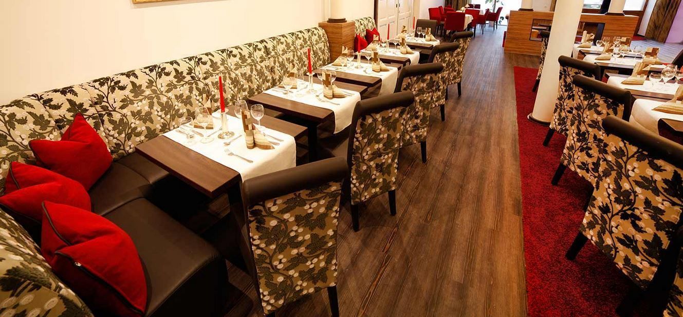 A restaurant with a long counter, multiple tables, and chairs.