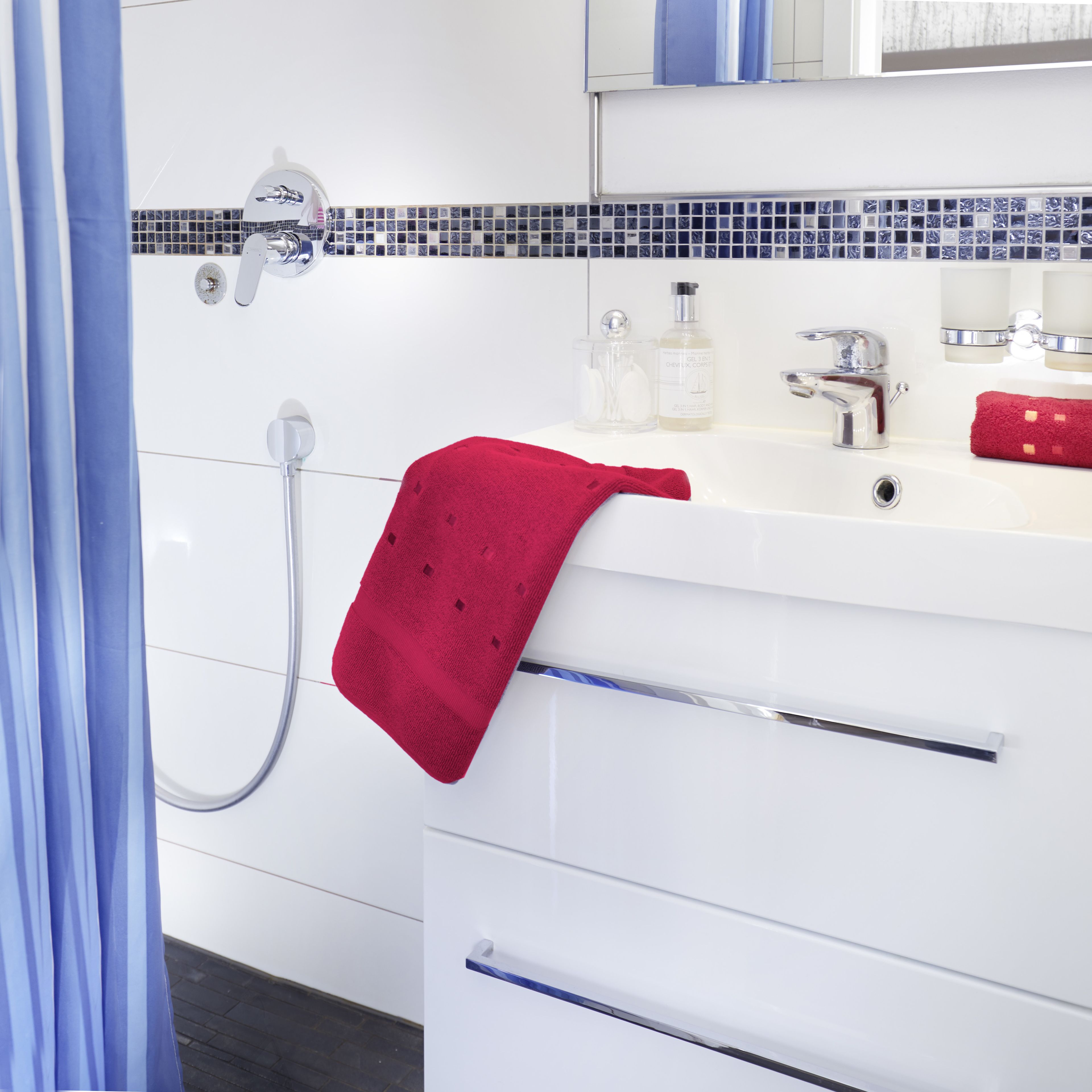 A bathroom with a white sink, a red towel, and a shower with a chrome faucet.