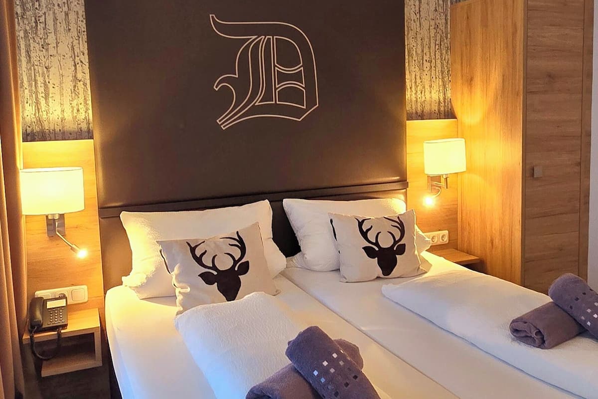 Ein Hotelzimmer mit einem großen Bett, zwei Nachttischen inklusive Lampen und einem Kleiderschrank.