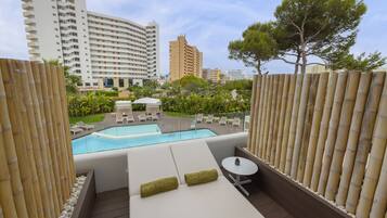 A rooftop pool area with lounge chairs, a small table, and a view of surrounding buildings.