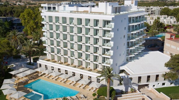 Un hotel moderno con varios pisos, piscina en la azotea y un jardín bien cuidado.