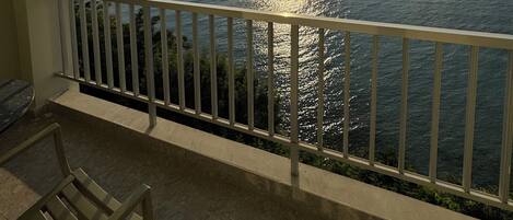 A balcony with a view of the sea and a sunset.