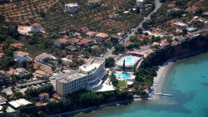An aerial view of a coastal area with a large hotel featuring a pool and a beach. - Messinian Bay Hotel (Kalamata)