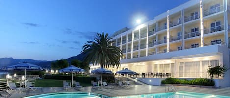 Un hotel con piscina, tumbonas y sombrillas.