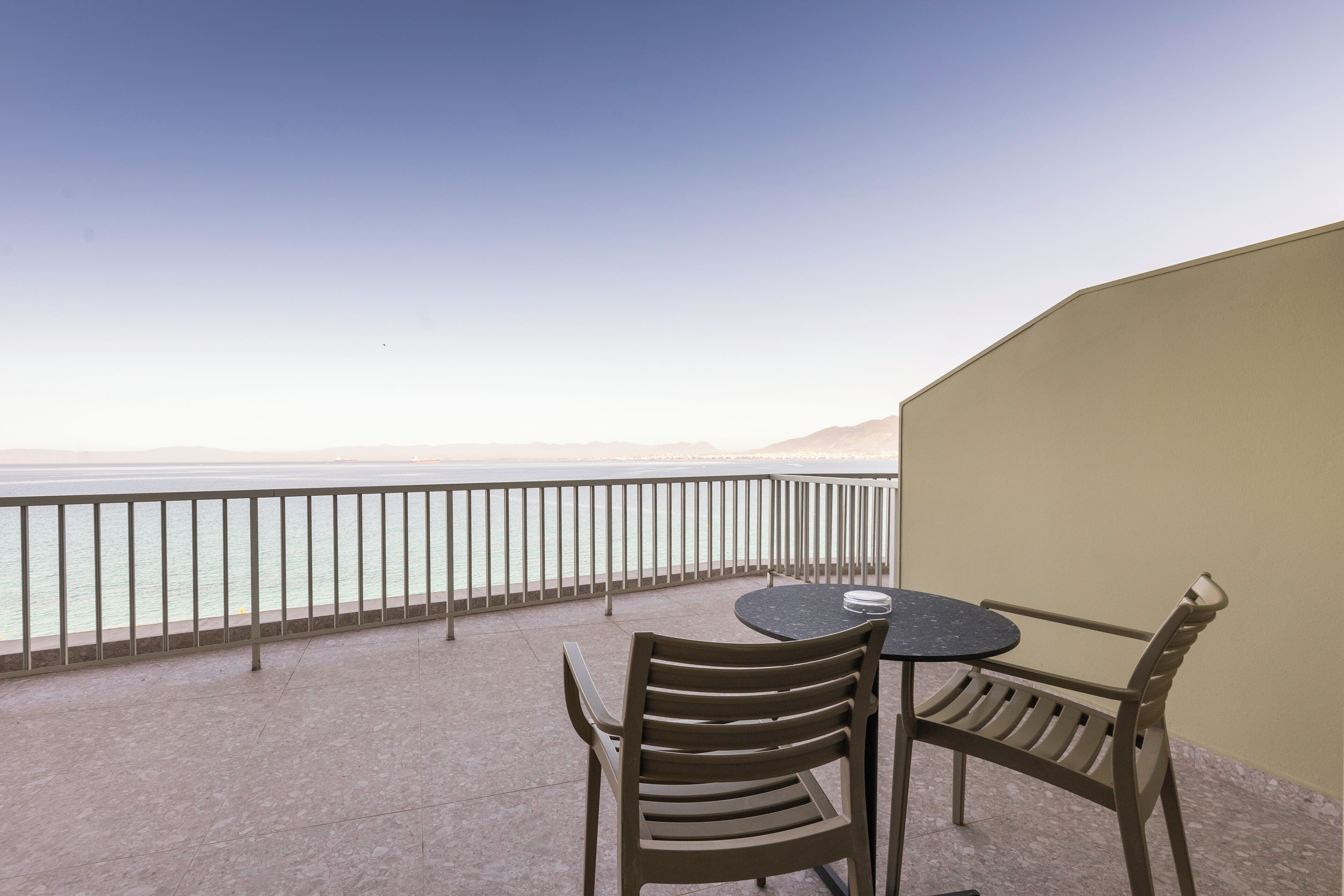 A balcony with a table and chairs overlooking a body of water.
