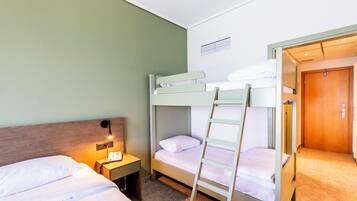 A bunk bed room with a wooden ladder, a bedside table with a lamp, and a door to another room.
