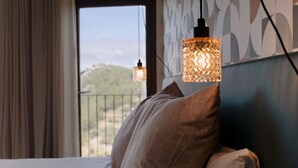 Une chambre d’hôtel avec un lit, un luminaire suspendu et une vue sur la verdure.