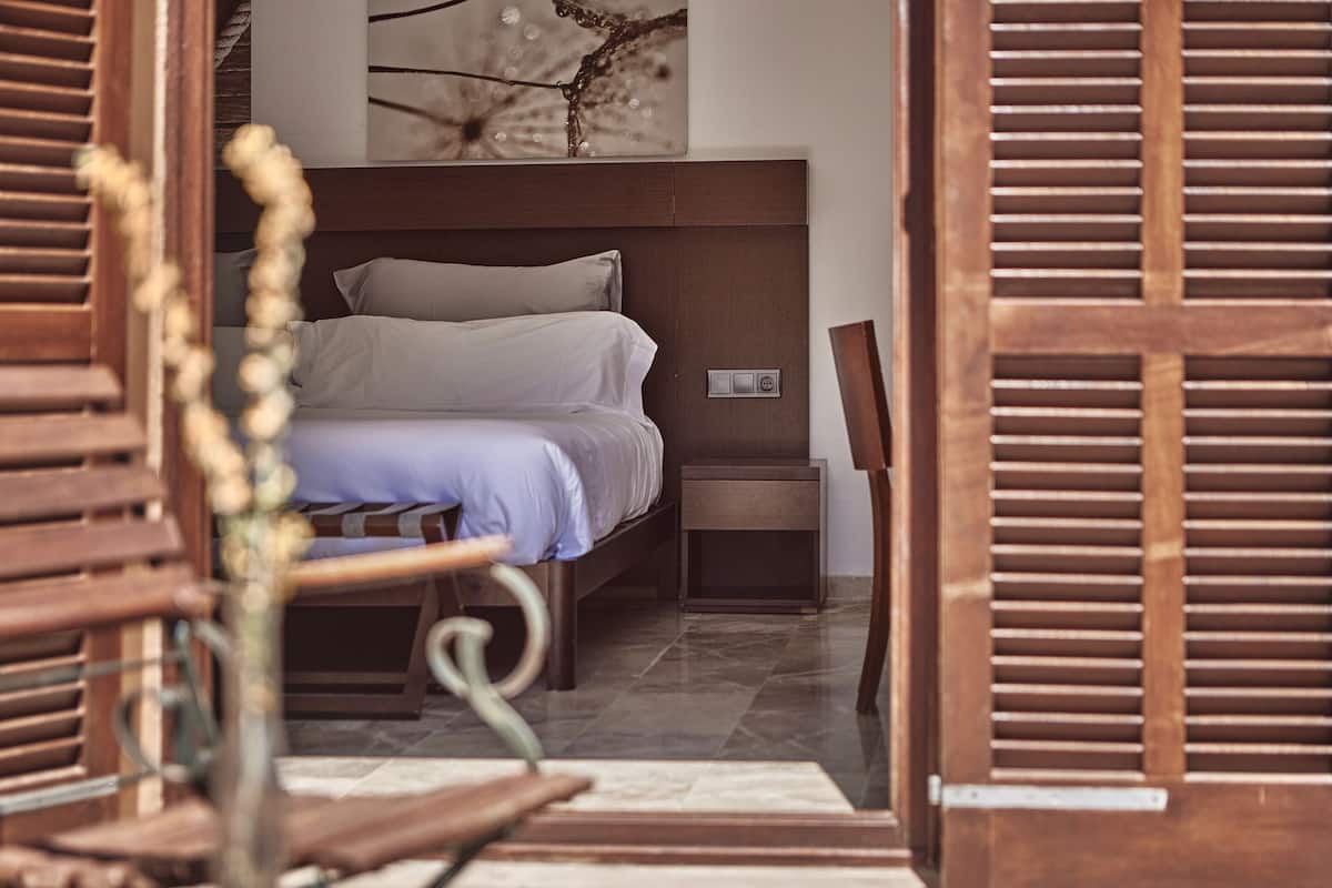 A bedroom with a bed, nightstand, and a wall-mounted light fixture.