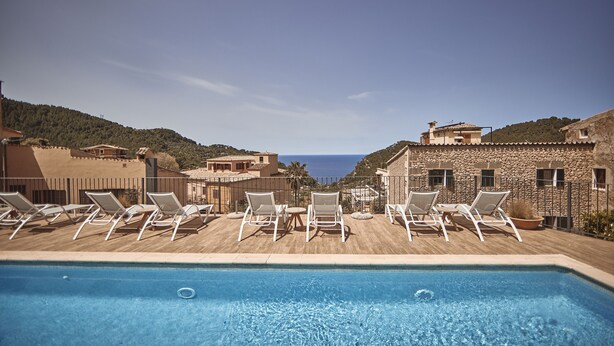 Un espace aménagé au bord de la piscine, avec des chaises longues et une vue sur la mer.