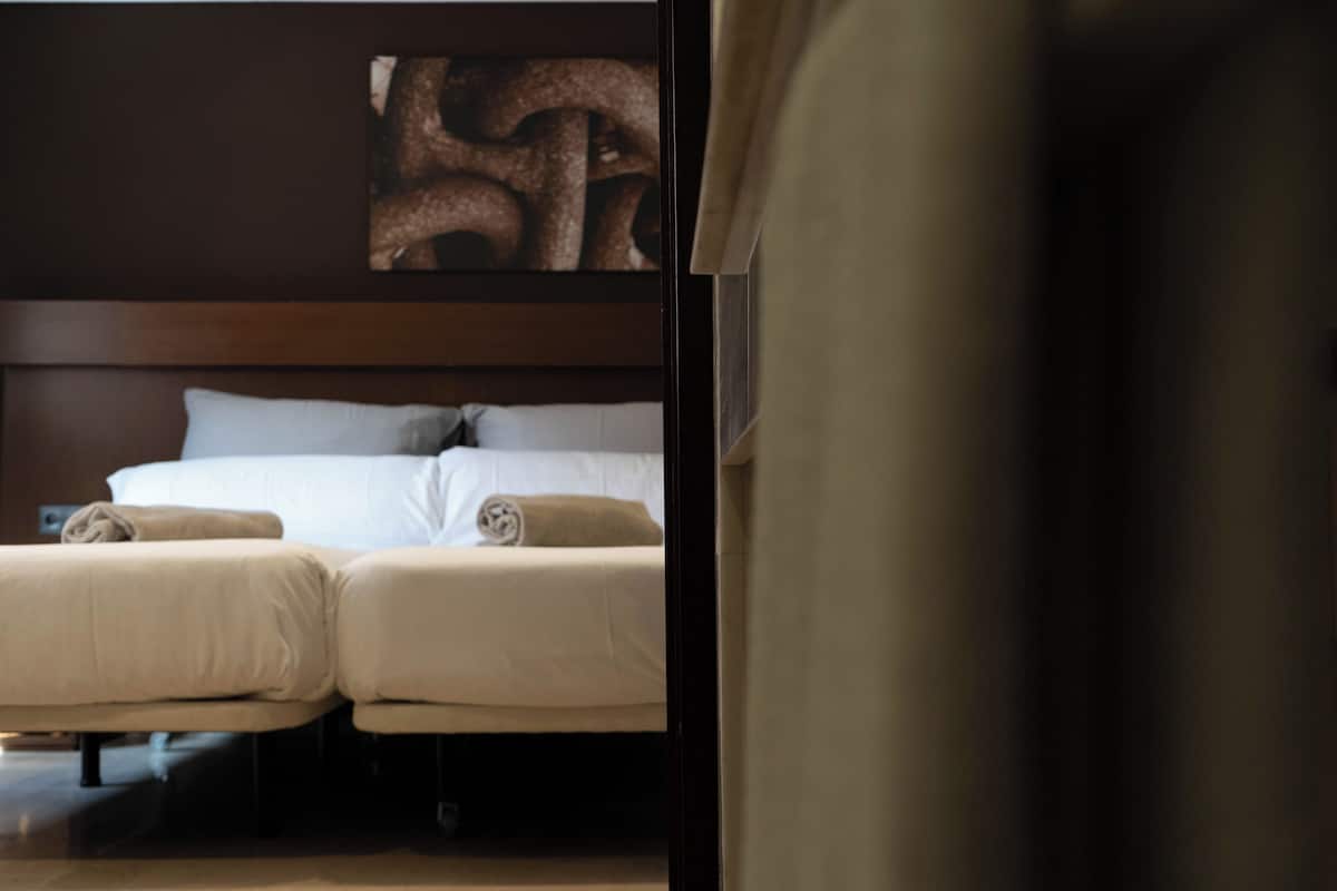A hotel room with a large bed, two bedside tables, and a headboard with a decorative panel.