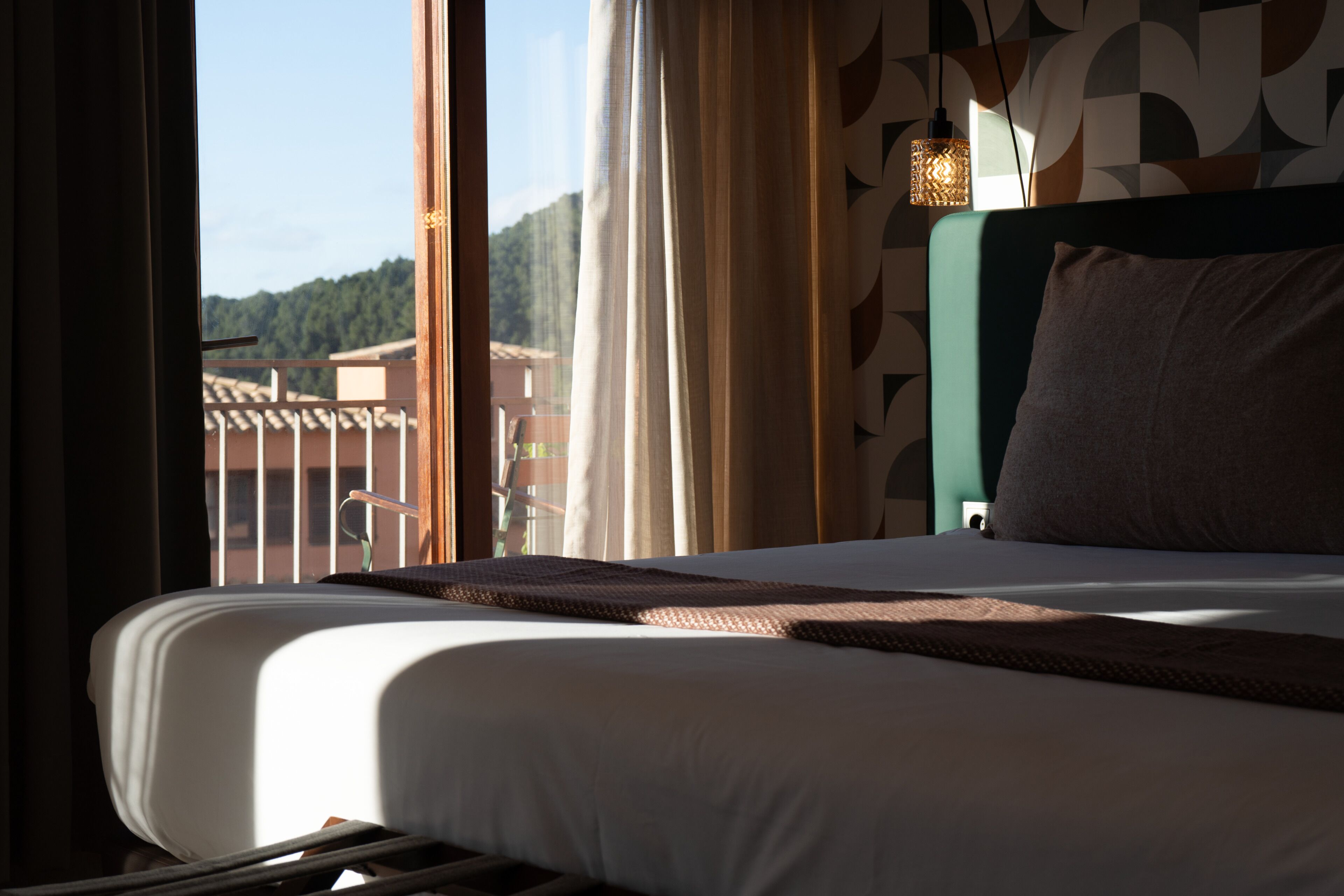 Habitación de hotel con cama, cortinas, vista a edificios y pared con diseño.