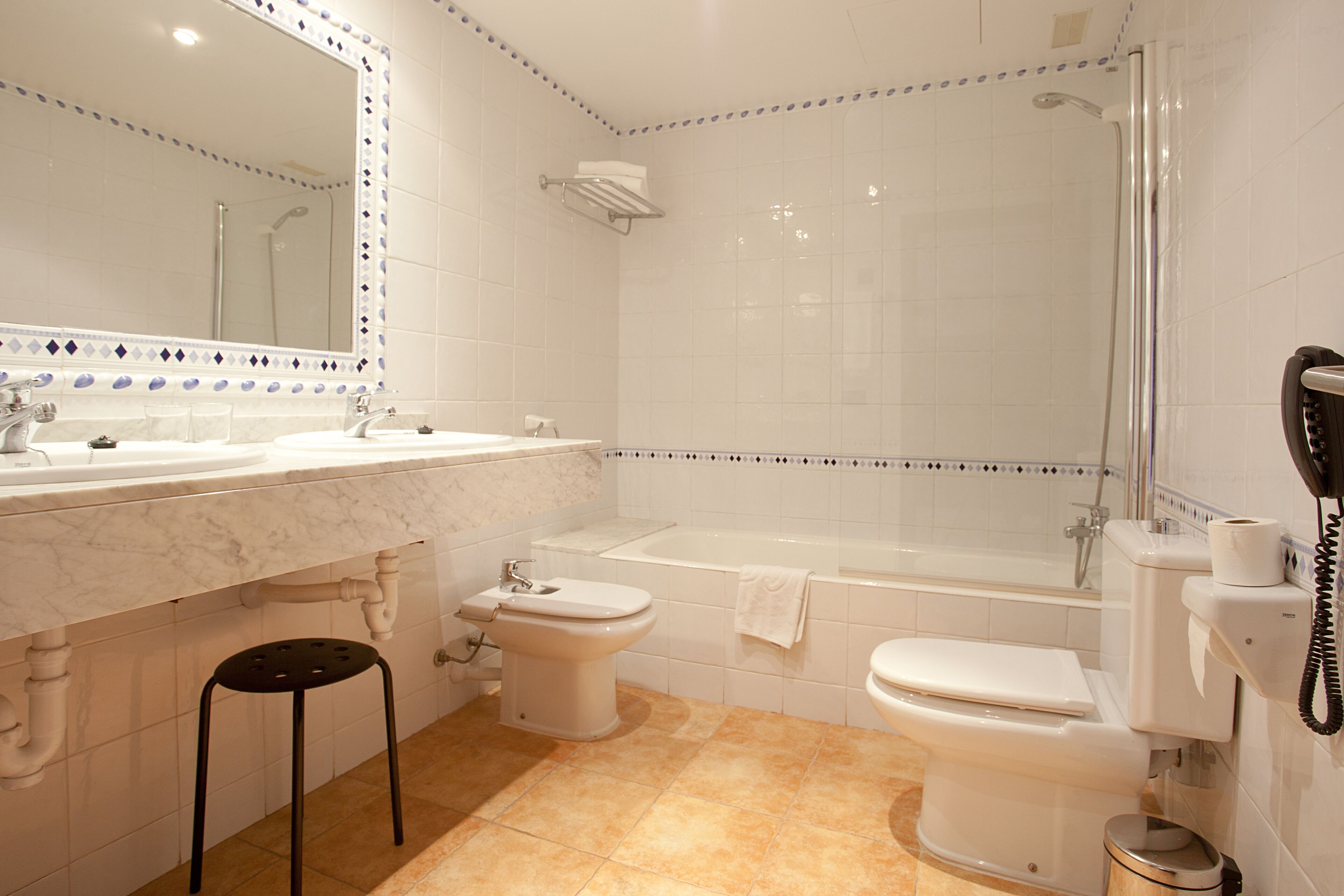 A bathroom with a double sink, toilet, bathtub, and a shower.