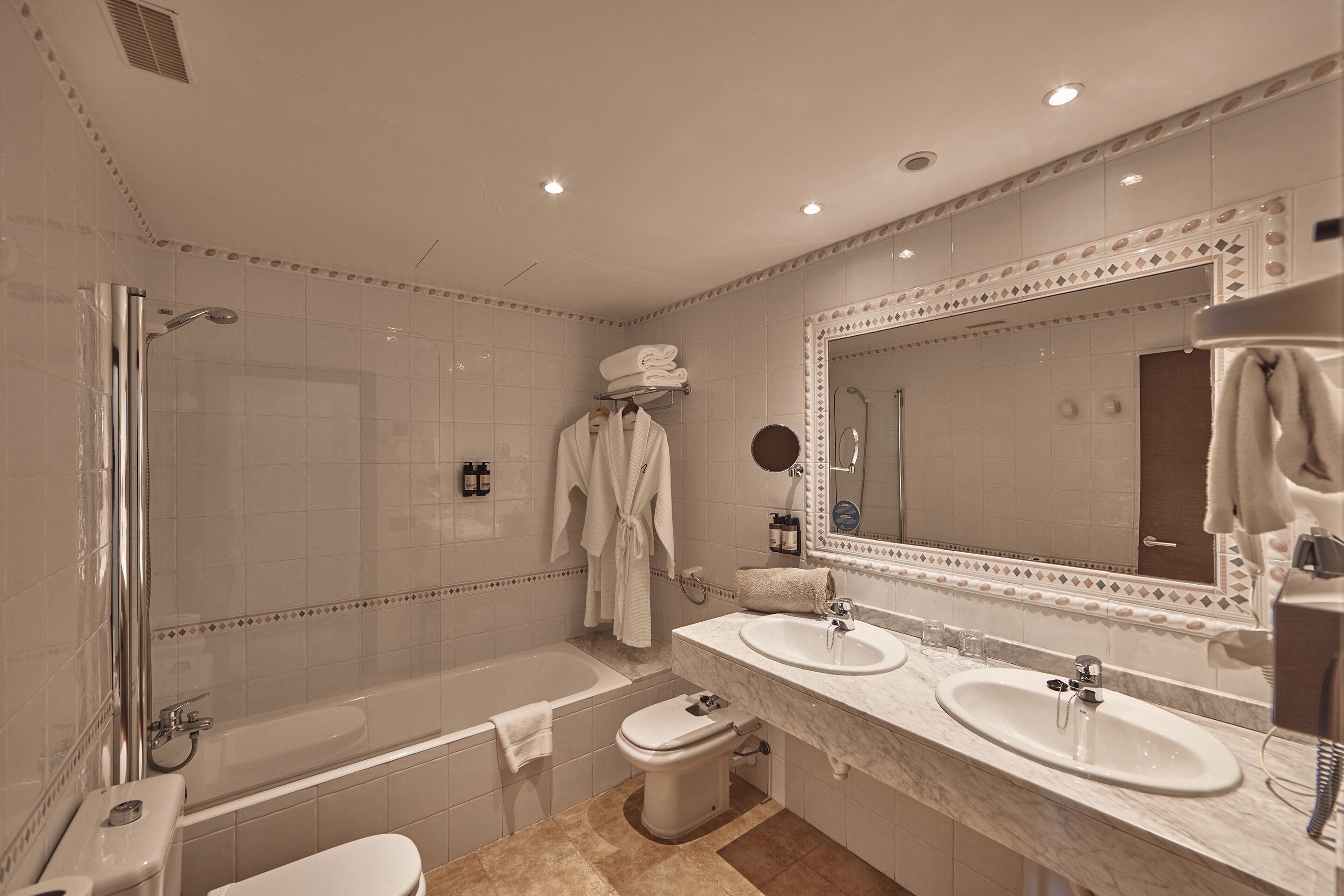 A modern bathroom with a bathtub, a shower, a toilet, and a vanity with a sink and mirror.