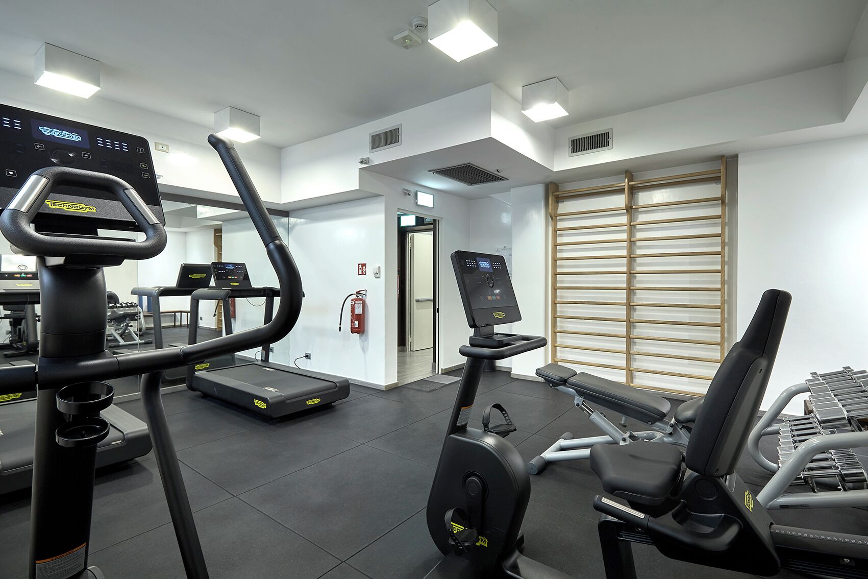 A gym with cardio machines, a treadmill, and a rowing machine.