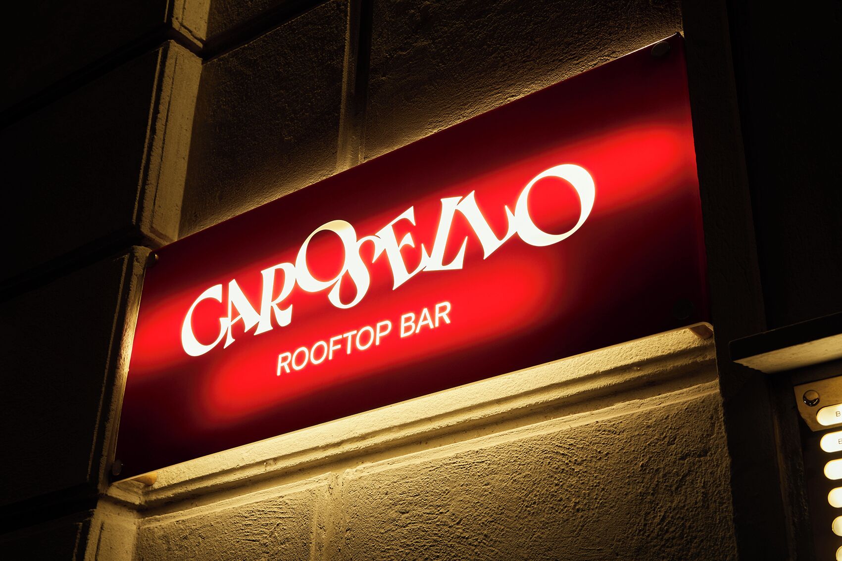 Ein Schild für die 'CARPELO ROOFTOP BAR' mit rotem Hintergrund und weißer Schrift.