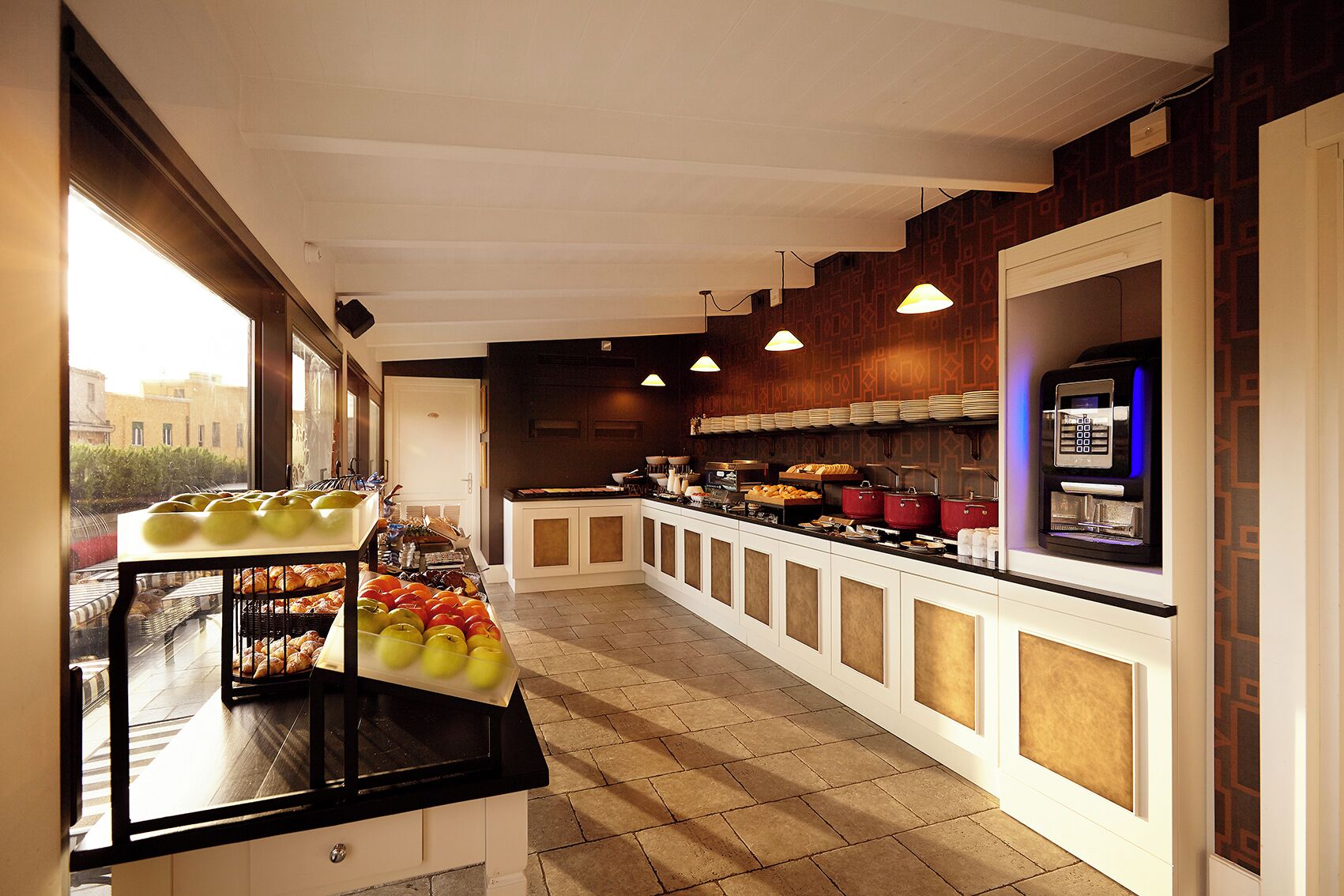 Une cuisine d’hôtel avec un buffet, comprenant un présentoir de fruits et différents stands de restauration.