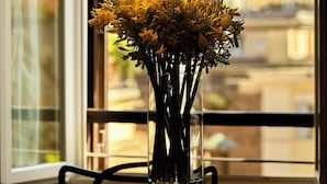 A table with a vase of flowers and a hanging lamp.