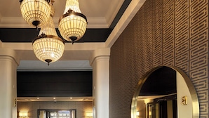 A lobby with a reception desk, a large mirror, and a chandelier.