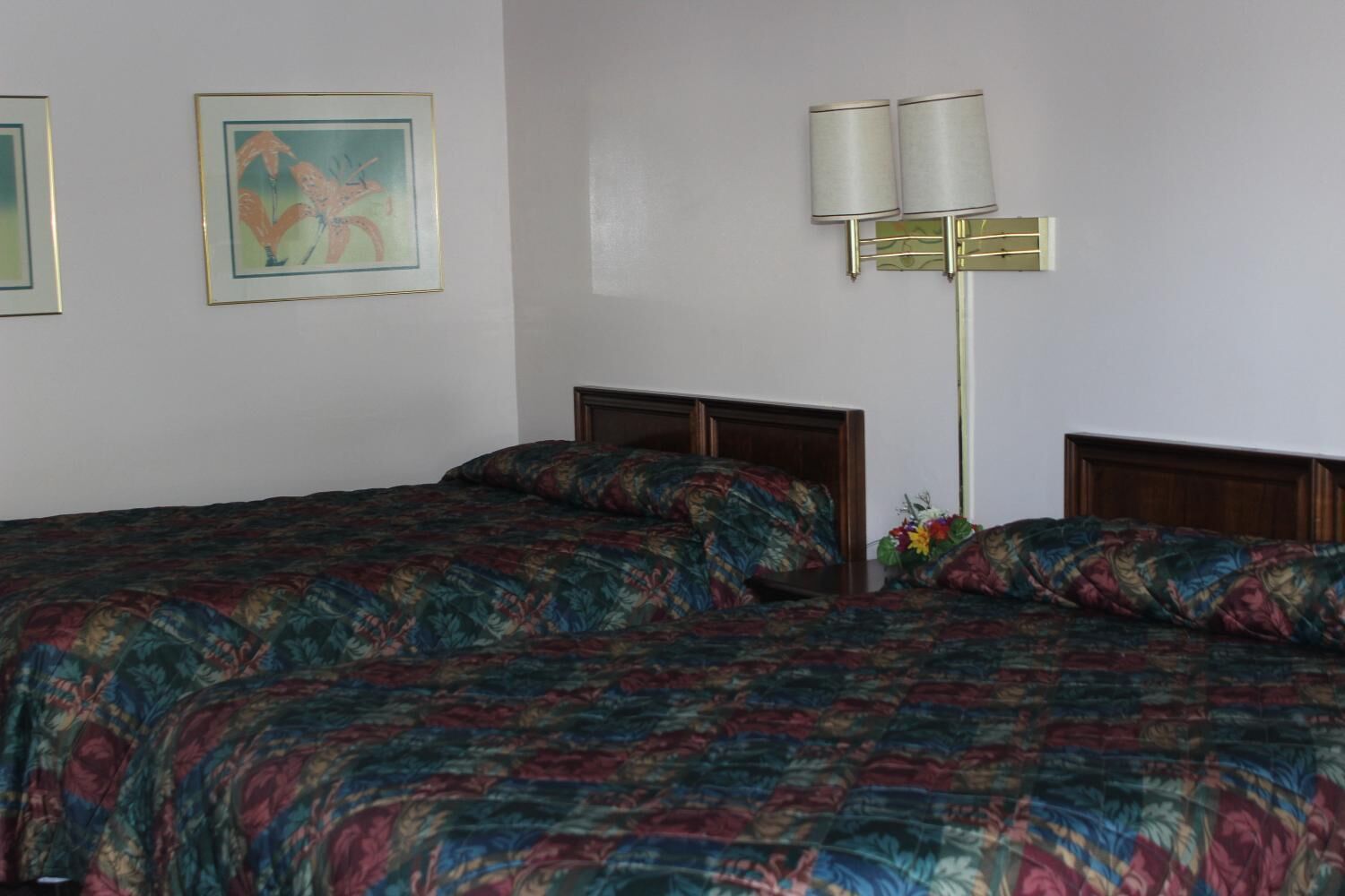 A hotel room with a large bed, a nightstand, a lamp, and a painting on the wall.