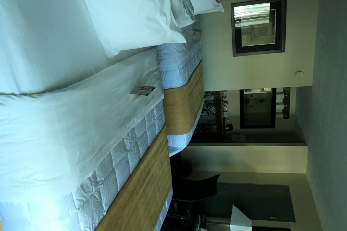 A hotel room with three beds, a desk, and a mirror.