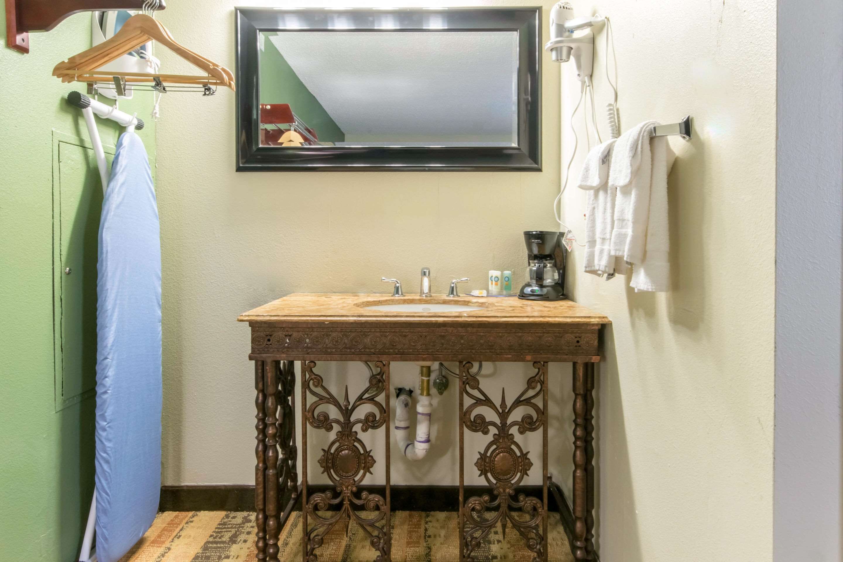 A bathroom with a wooden vanity, a mirror, a sink, and a towel rack.