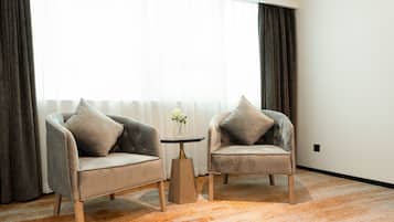Una habitación con dos sillones, una mesita y un florero con flores.