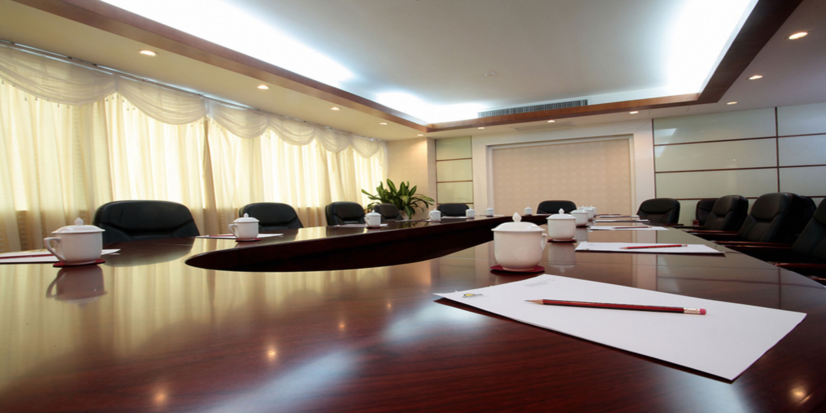 Une salle de conférence avec une longue table, des chaises et un tableau blanc.