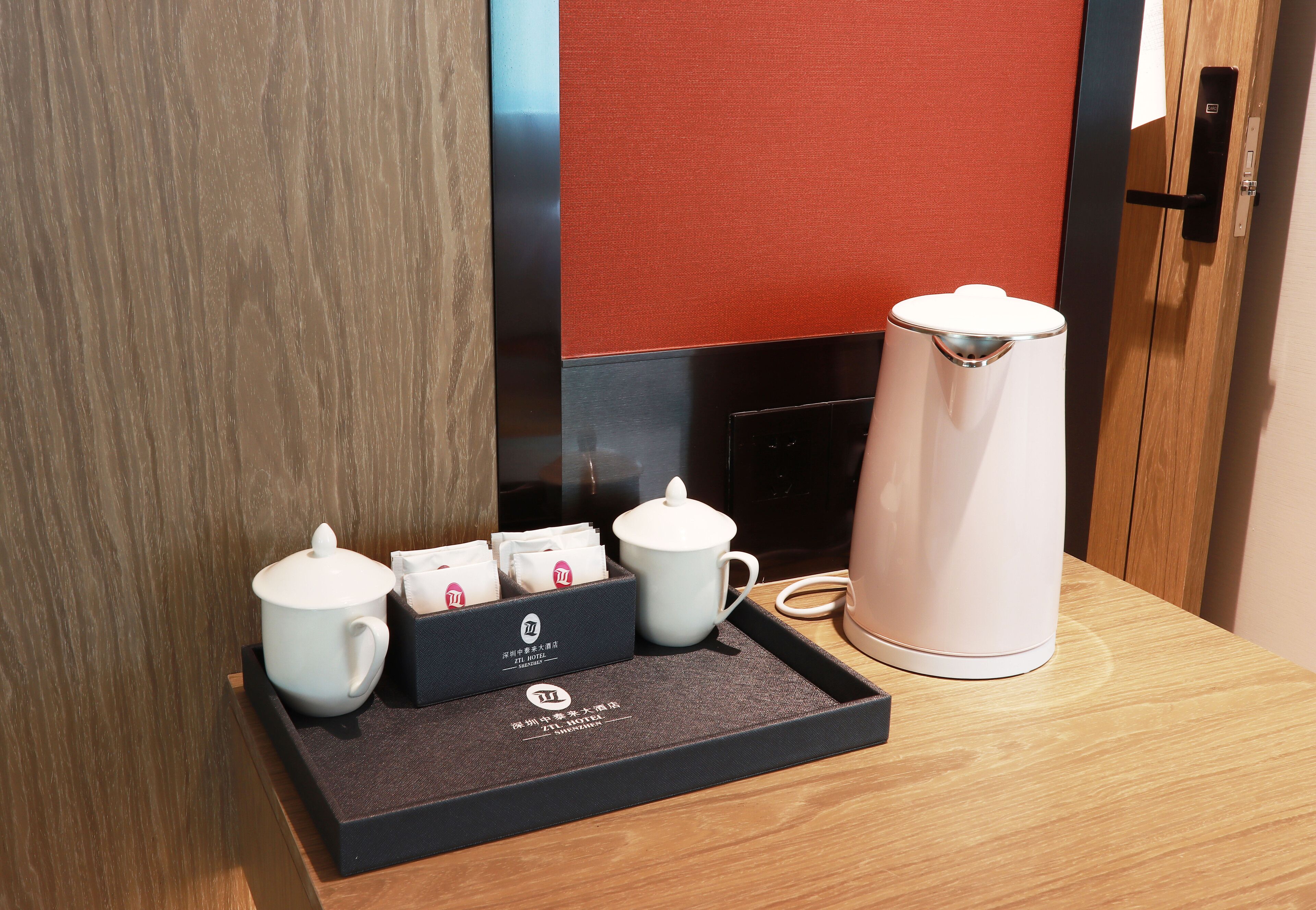 Un plateau avec une théière, deux tasses et une boîte de sachets de thé, posé sur une table en bois.