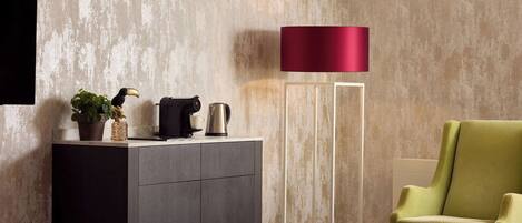A modern room with a grey cabinet, a red floor lamp, a green armchair, and a small table.